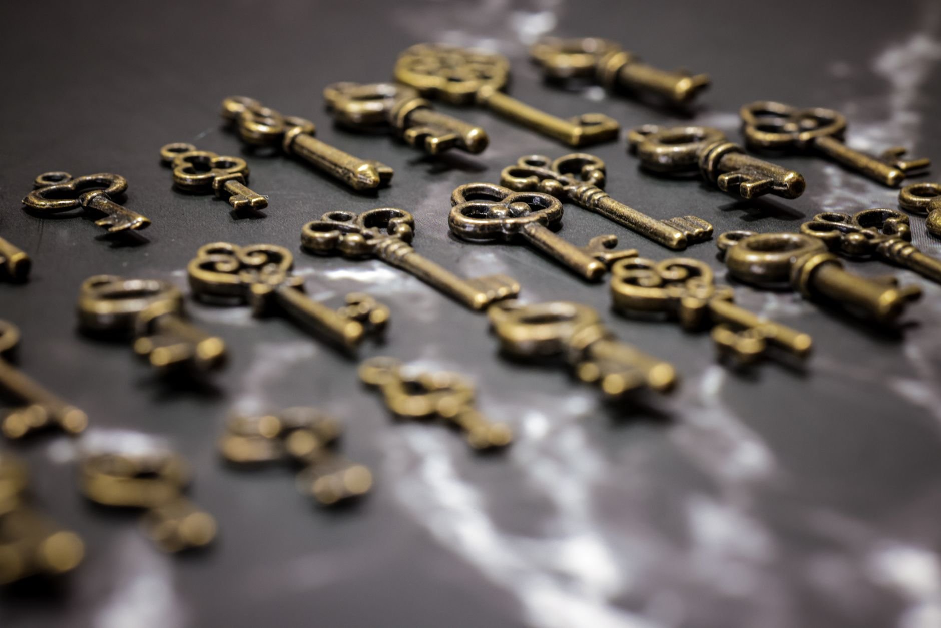 A collection of vintage brass keys scattered on a dark surface.